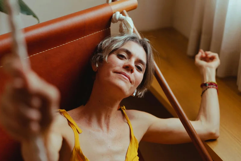 Femme cinquantenaire détendue dans son fauteuil, regard confiant et sourire serein, illustration du bien-être après 50 ans